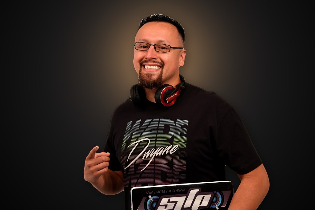 DJ LS (Juan Zafra) smiling with headphones, pointing